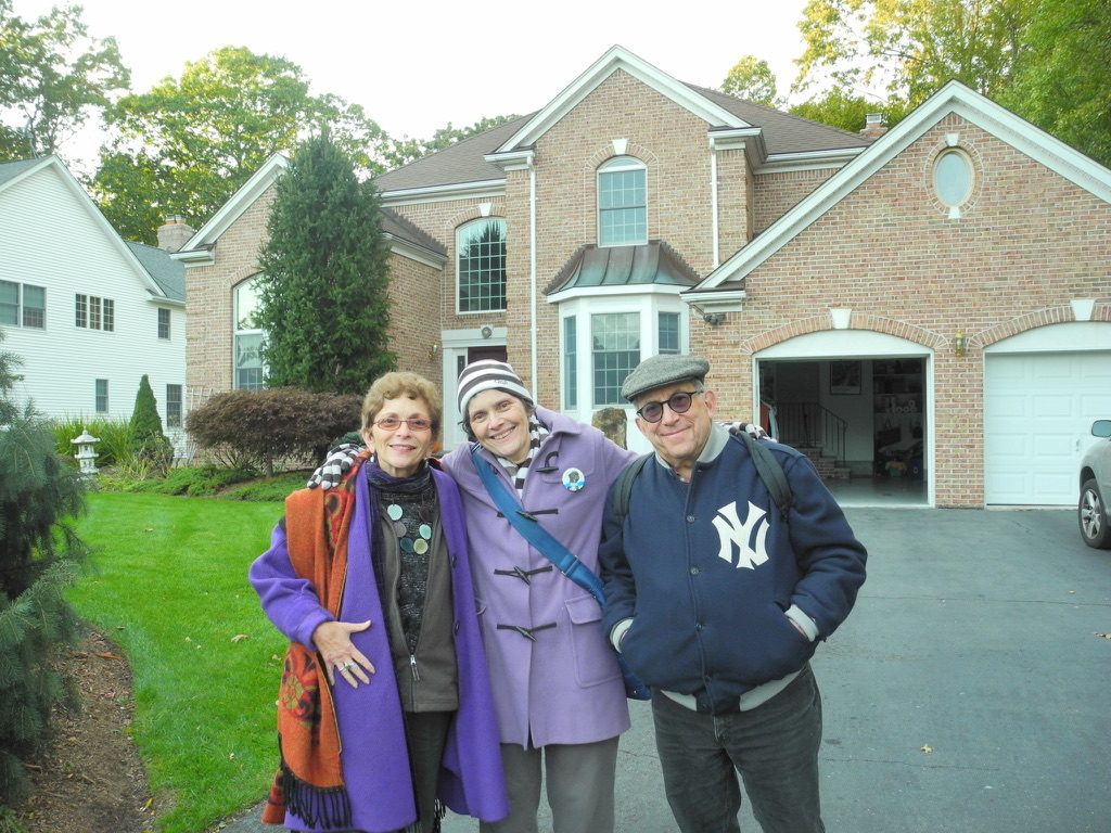 David and two women standing in front of a brick house