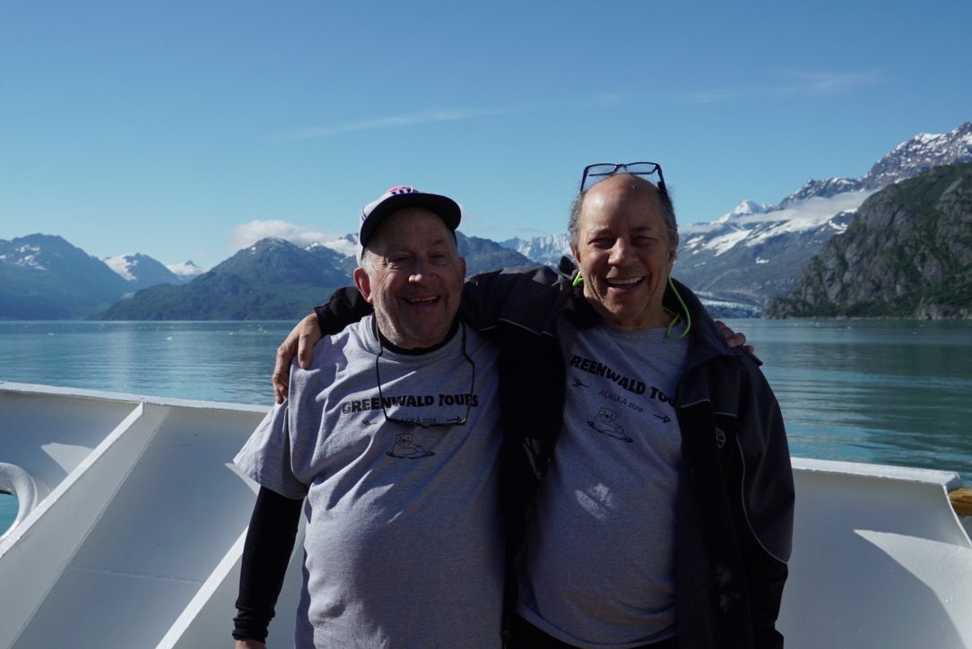 David and another man laughing with their arms around each other on a boat in Alaska