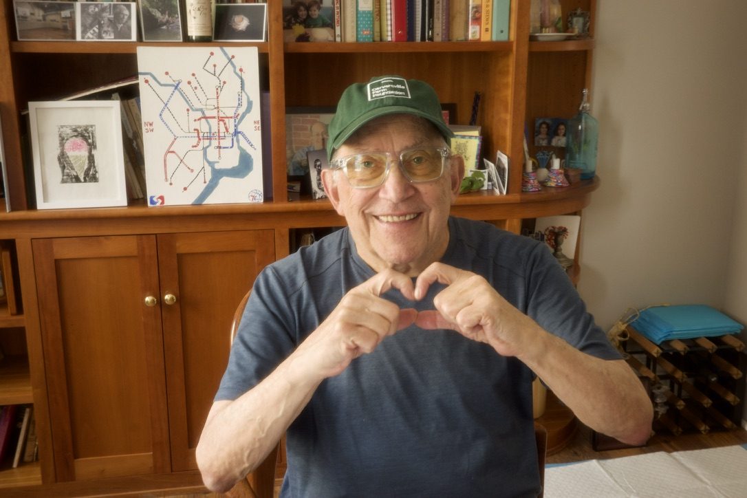 David making a heart with his hands in front of a bookshelf
