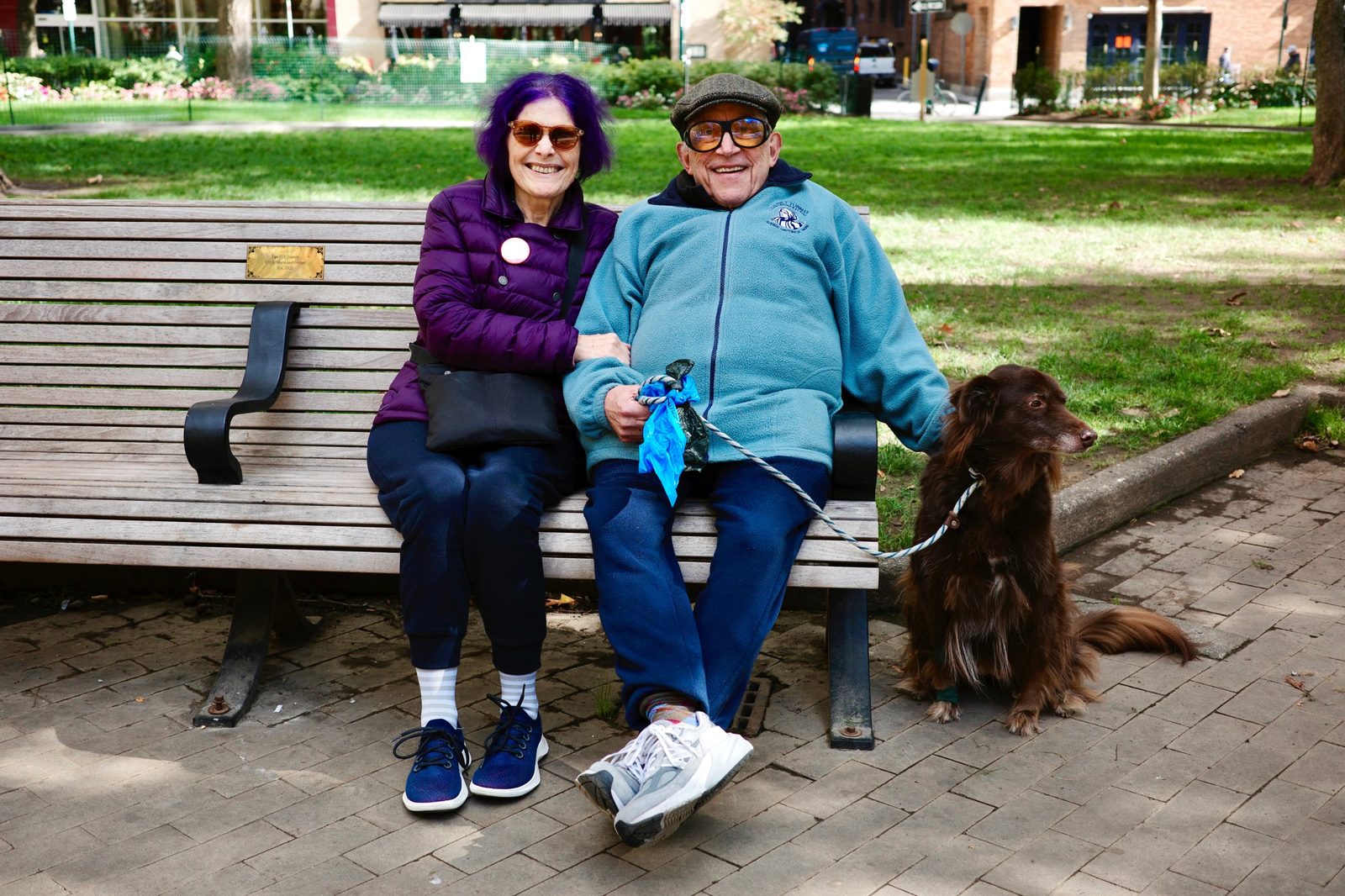 David and a woman on a park bench with a brown dog