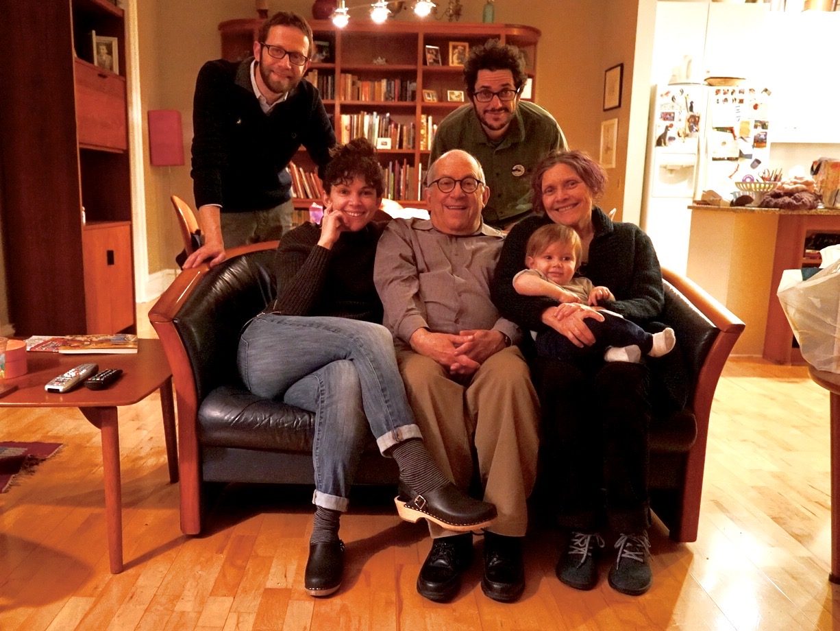 David seated on a couch with family, including a toddler