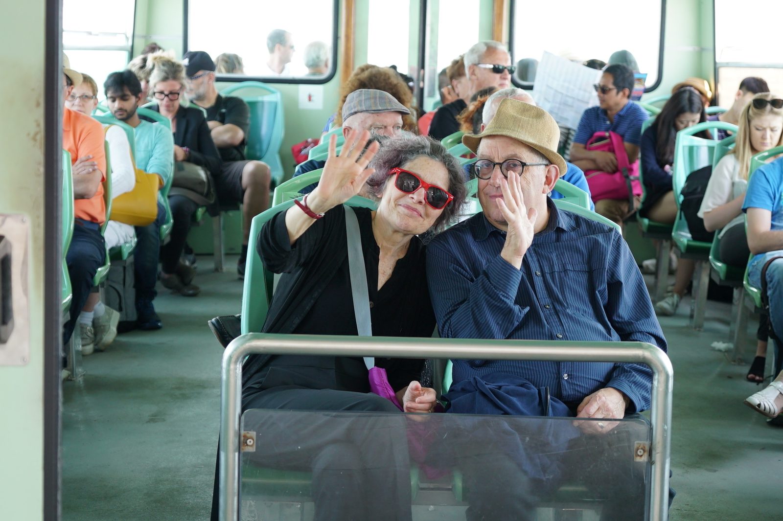 David and a woman waving from their seats on a Venice water bus