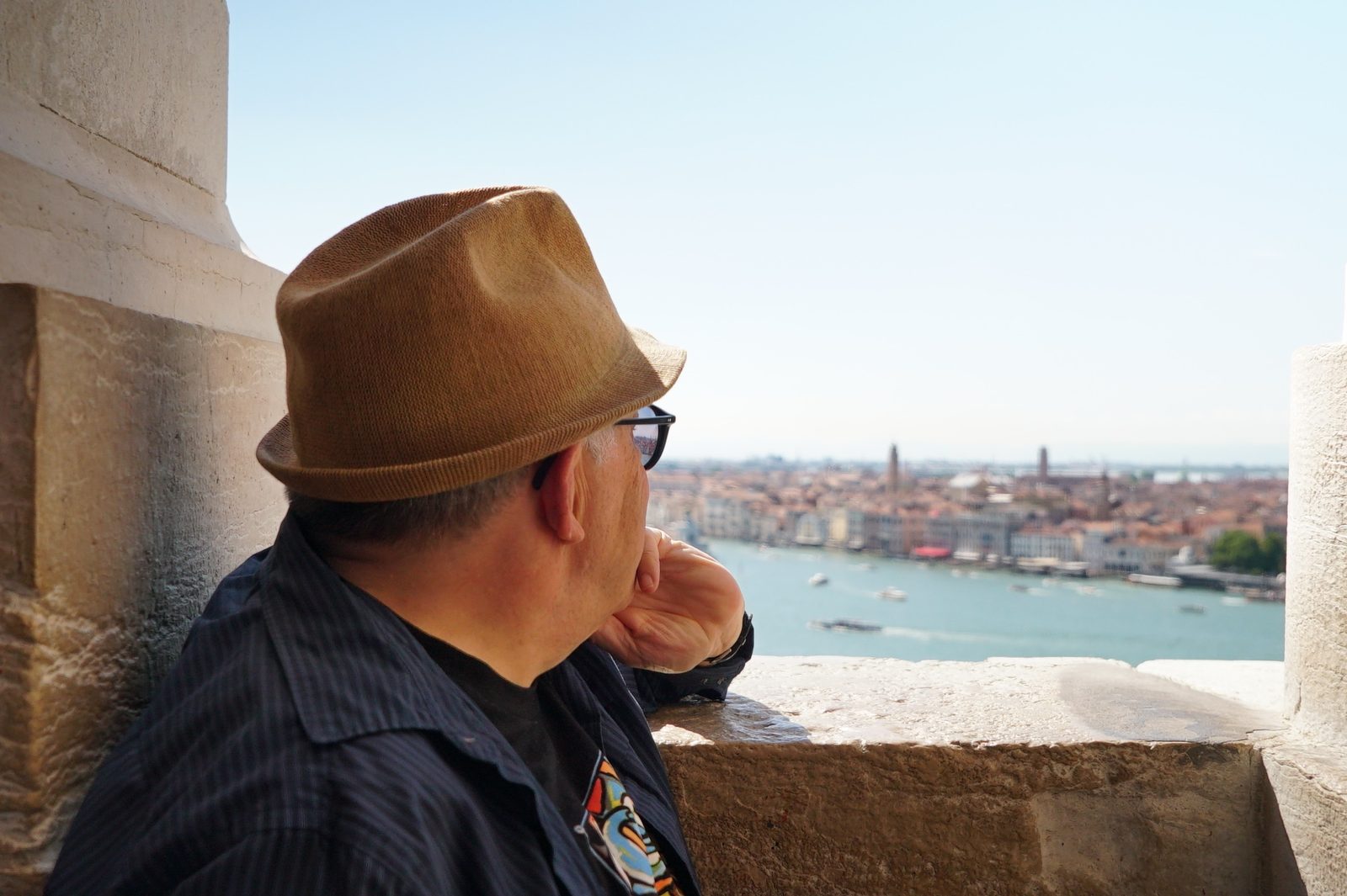 David in a straw hat looking out over Venice from a tower
