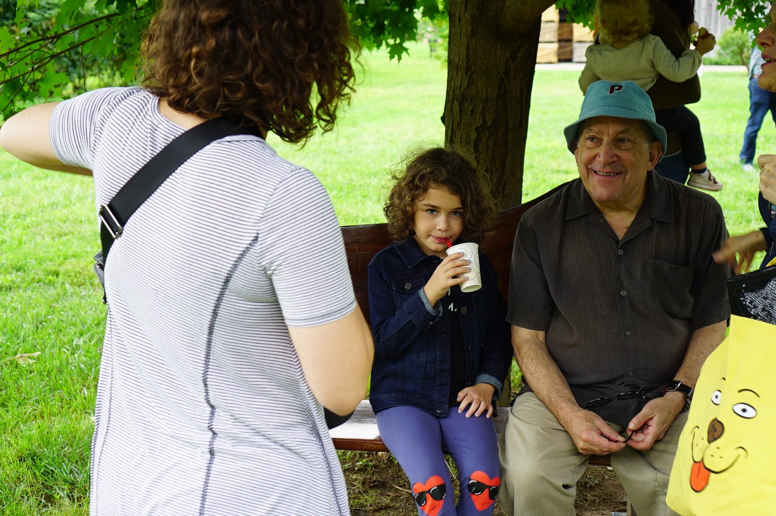 David smiling on a park bench next to a girl sipping a drink