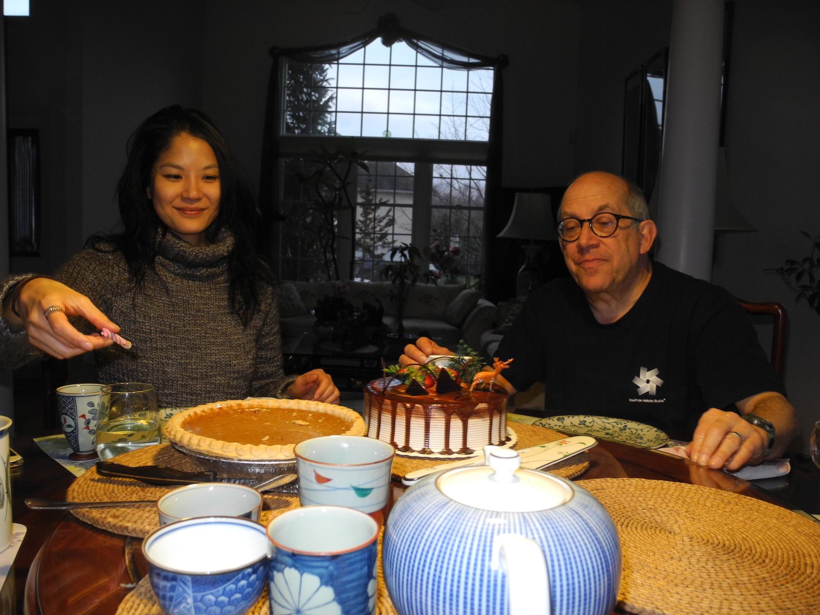 David at a dining table with a woman, a chocolate cake and a pie