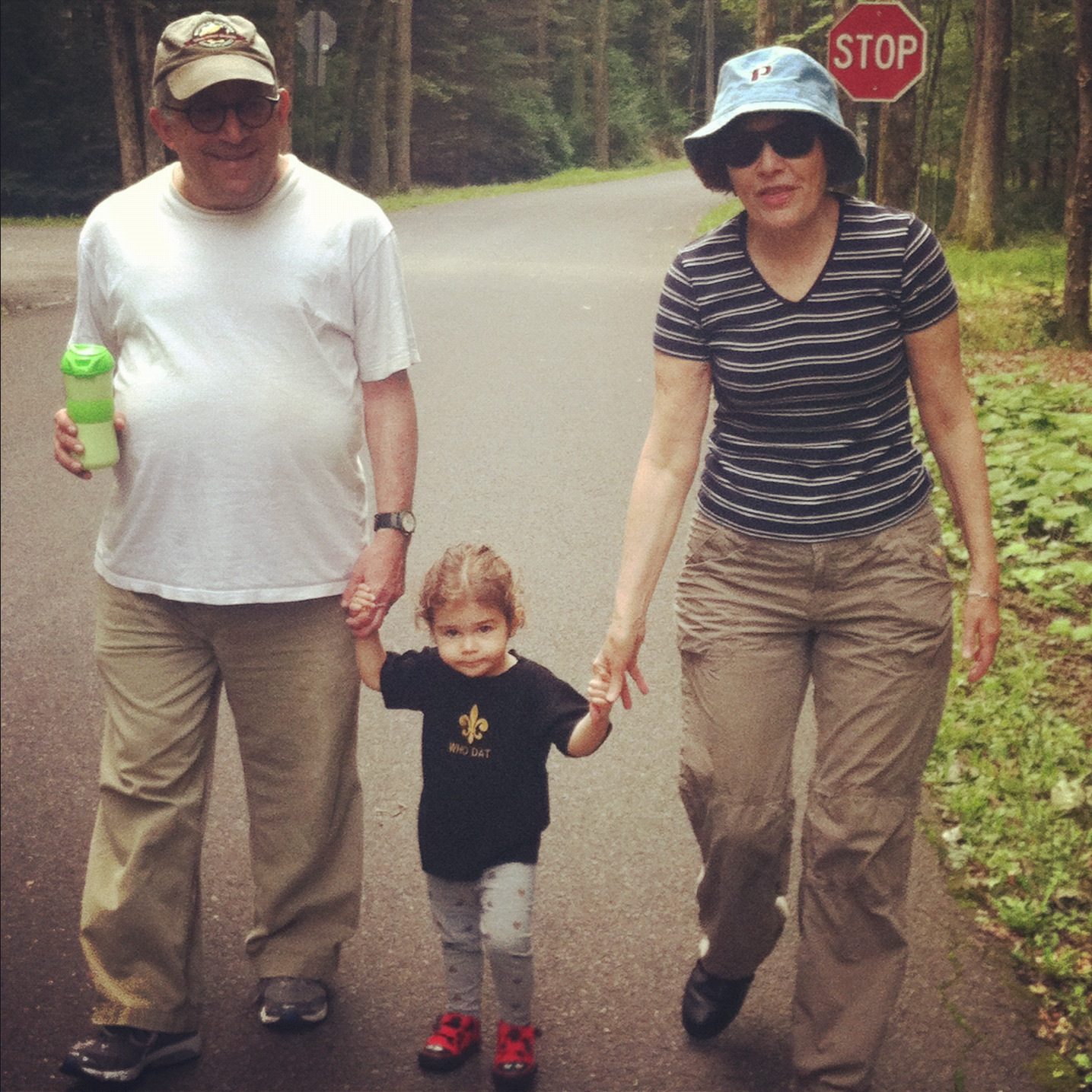 David and a woman walking hand in hand with a toddler on a road through the woods
