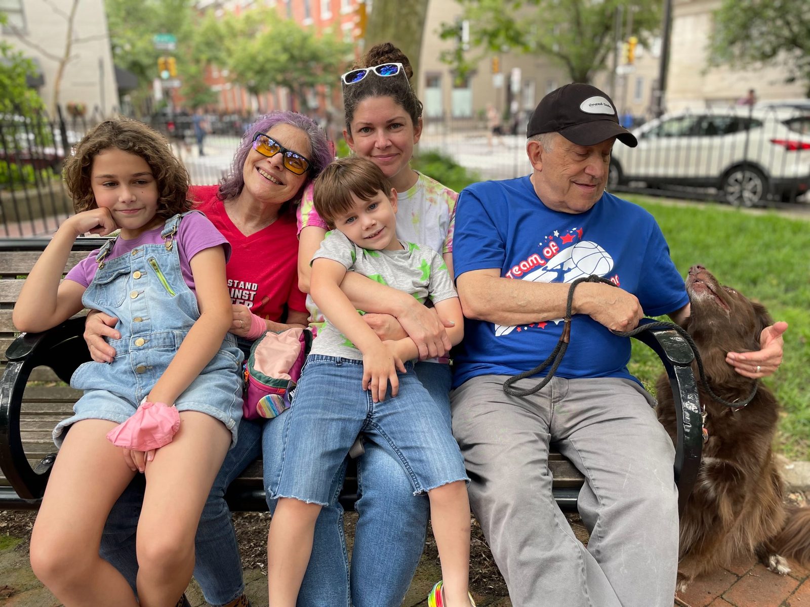 David with family and a brown dog on a park bench