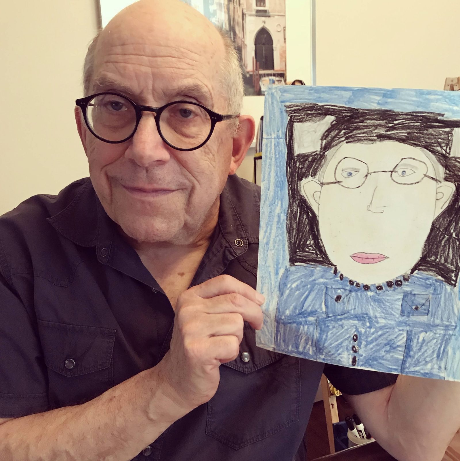 David holding up a child's drawing of a woman with glasses