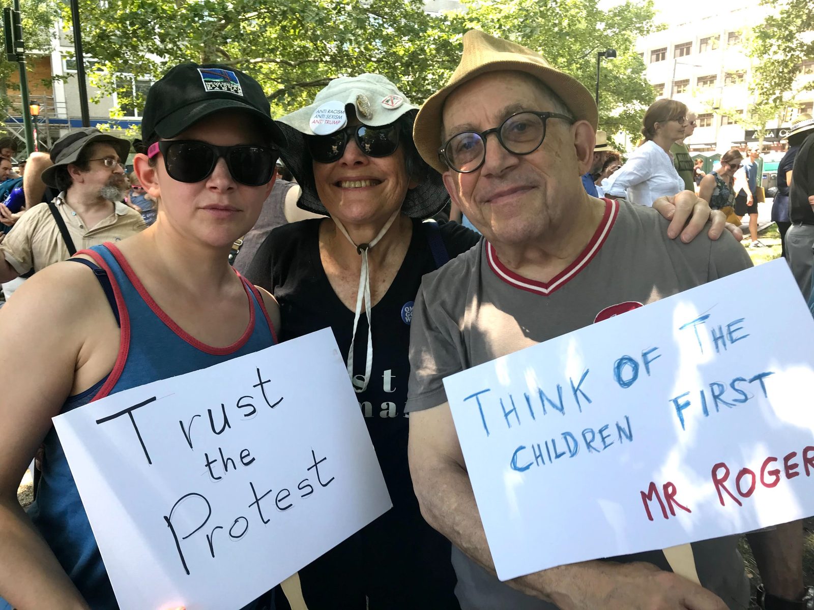 David and two women holding hand-lettered protest signs outdoors
