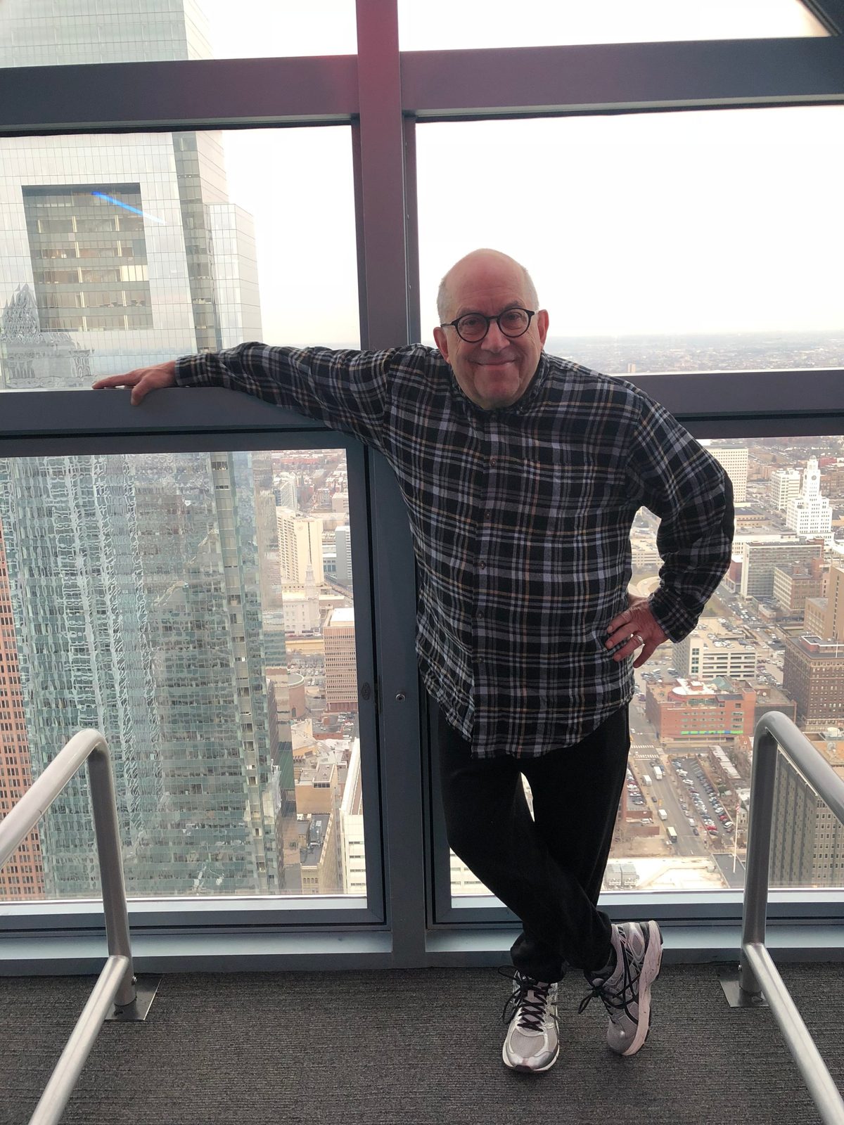 David standing at a tall window high above the city