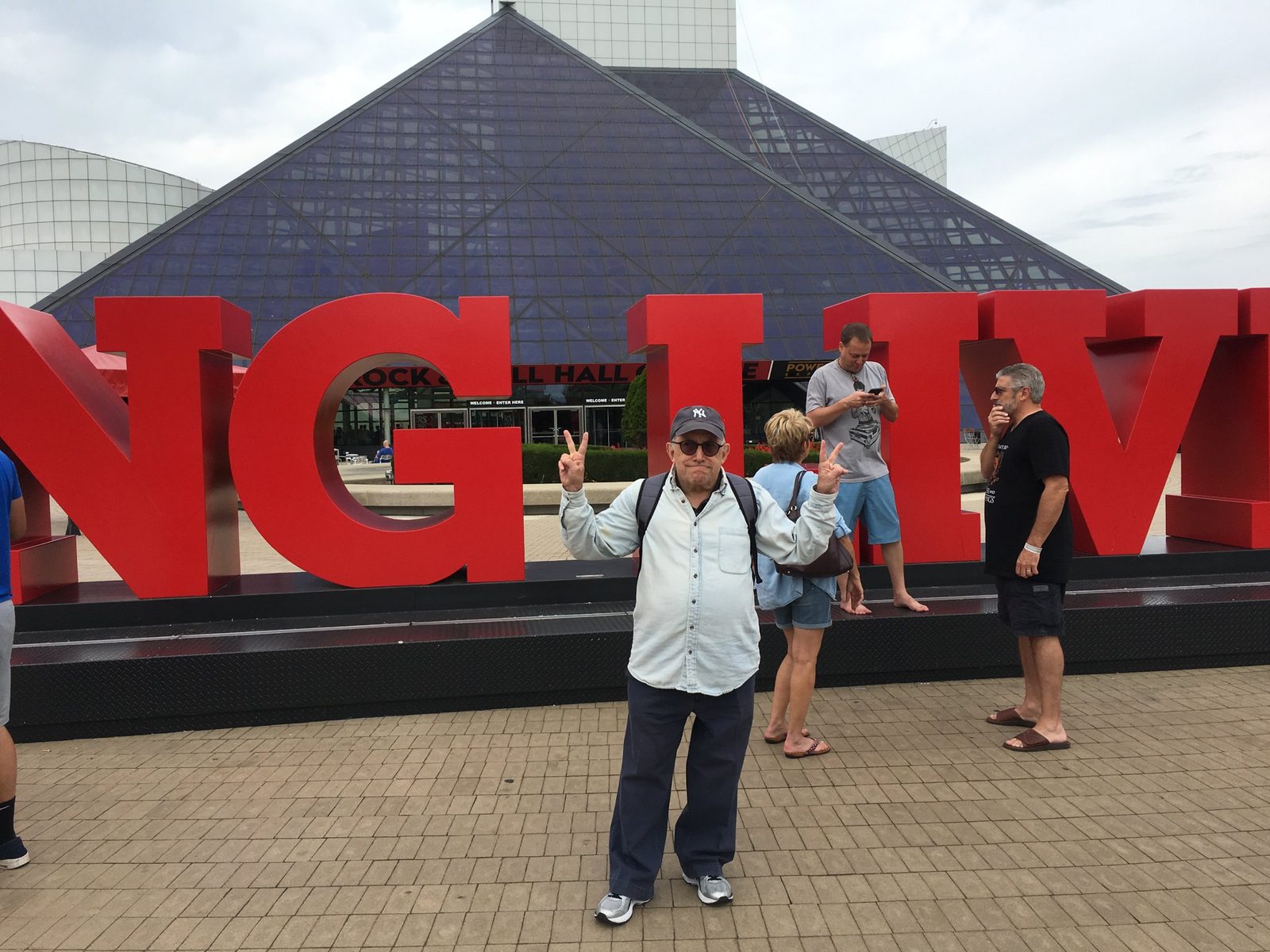 David in a Yankees cap making peace signs in front of the Rock and Roll Hall of Fame