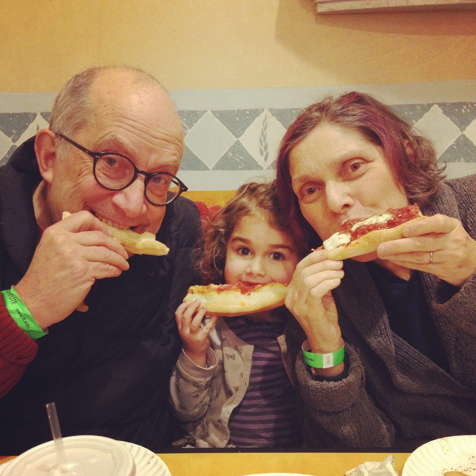 David, a young girl and a woman biting into slices of pizza