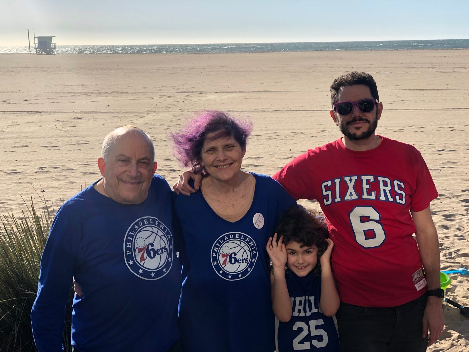David, a woman, a young girl and a man in Sixers shirts on a beach
