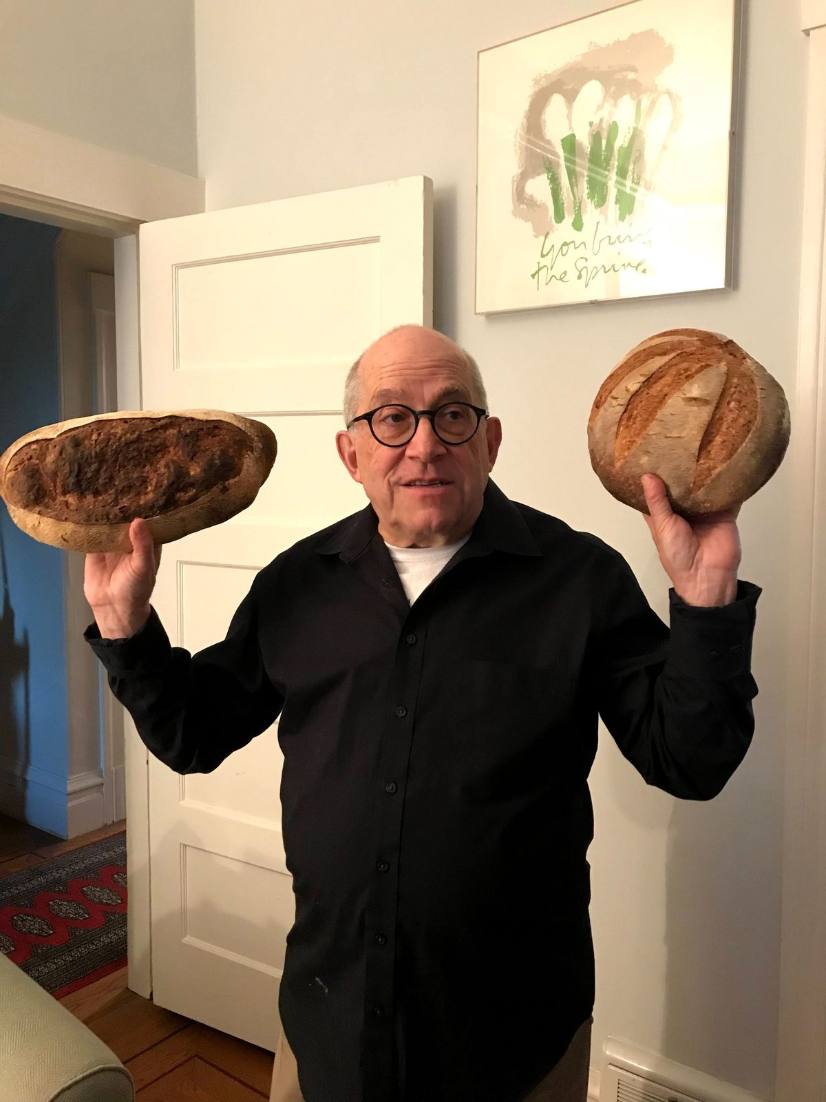 David holding up two loaves of bread, one dark and one round